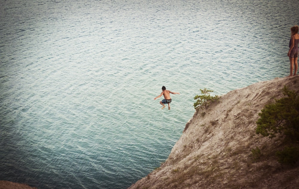 man jumping on body of water