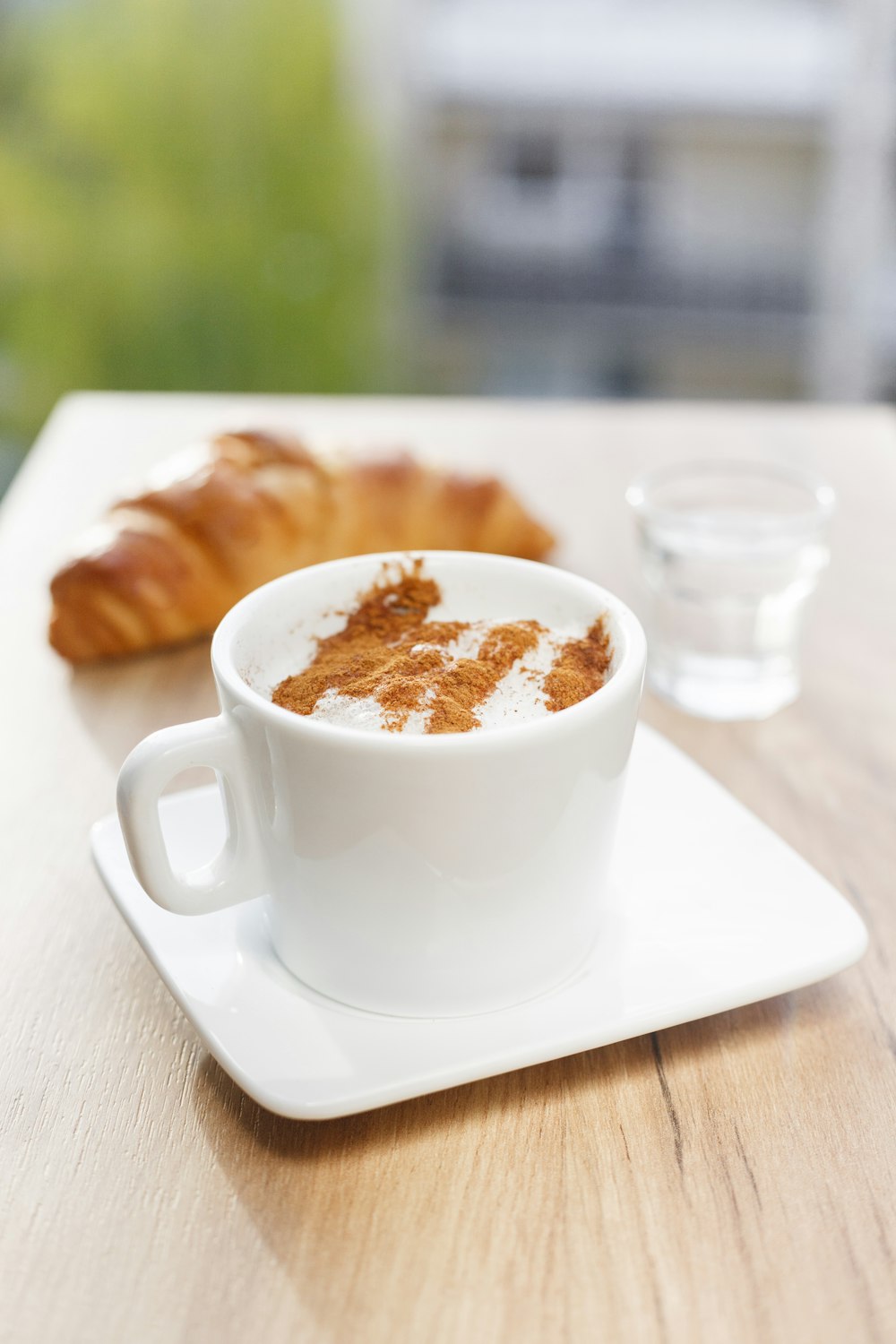 Fotografia plana de caneca branca no prato de pires branco e pão croshan