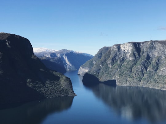 calm body of water between mountains under blue sky during daytime in Aurland Norway