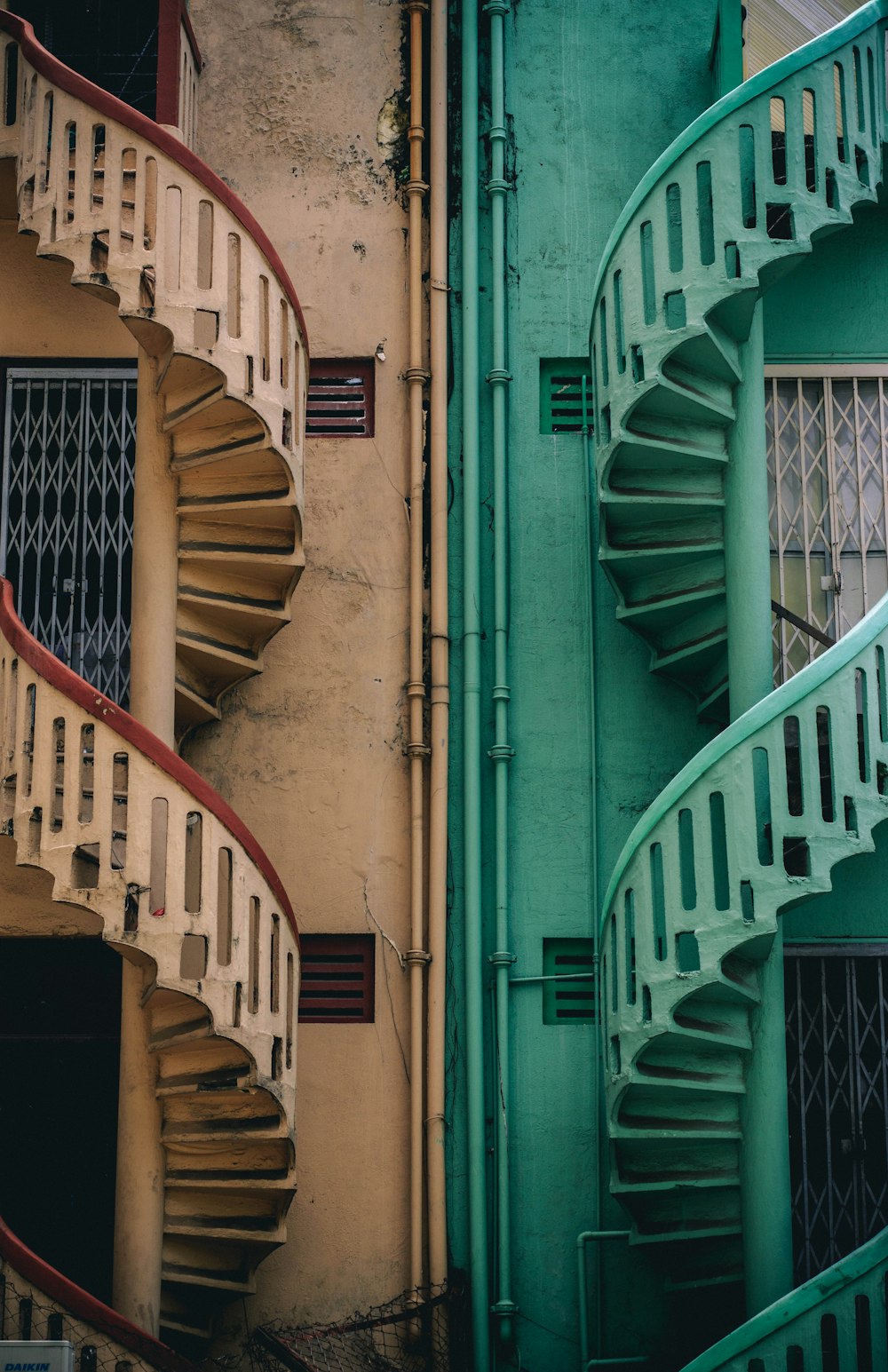 Escadas espirais de concreto bege e verde ao lado do edifício