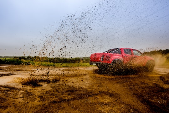 red 4-door truck on mud near trees under cloudy sky in Andenne Belgium