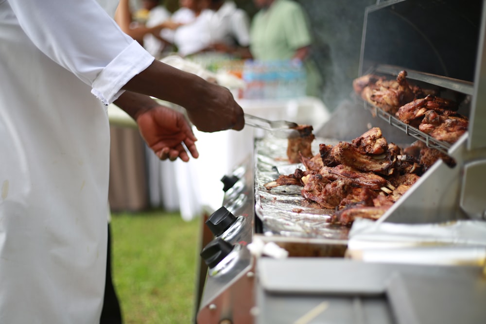 person in white shirt grilling meat