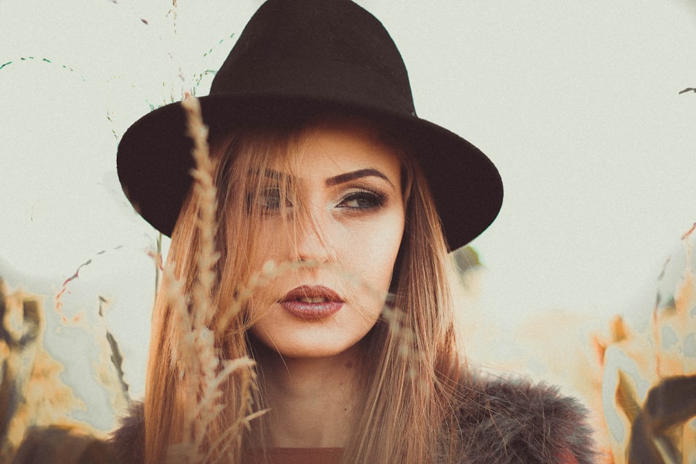 woman wearing black hat standing beside beige grass