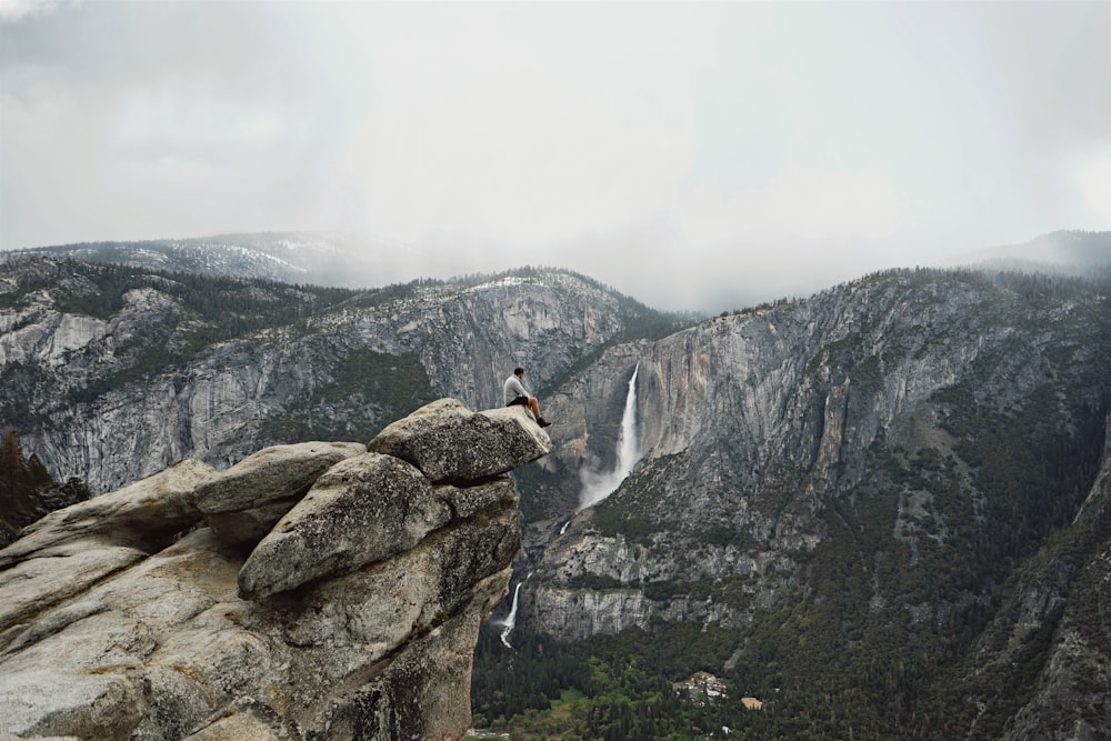 person sitting on mountain cliff