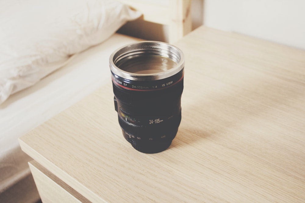 black DSLR camera lens travel mug on nightstand