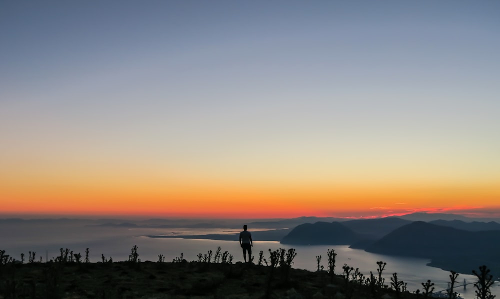 silhouette photo of man standing on mountain