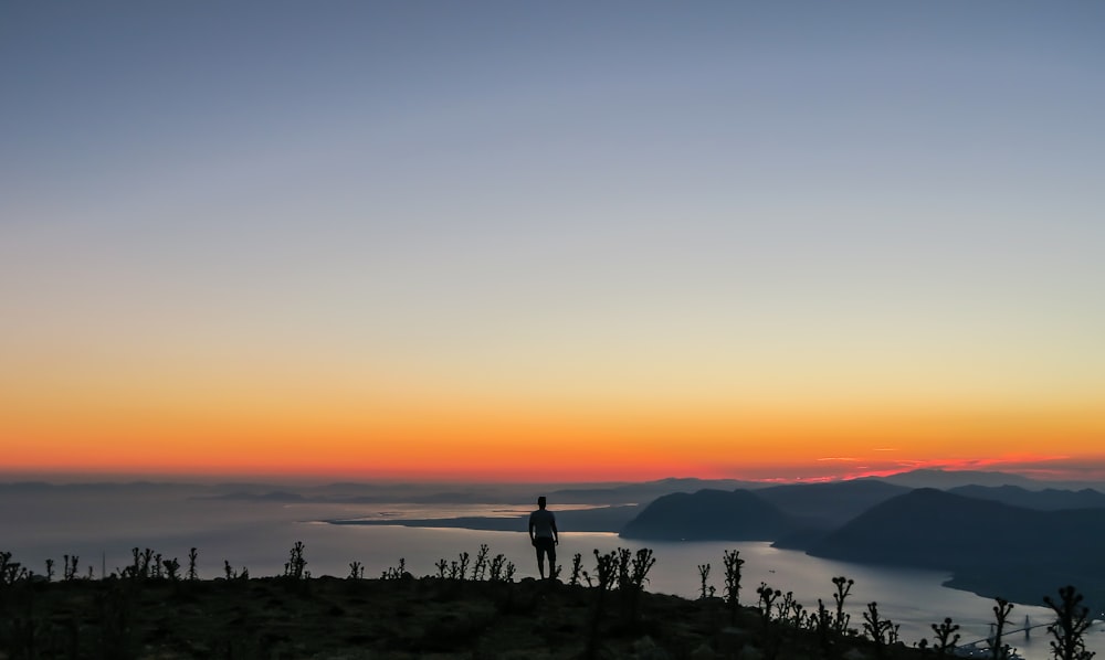 Silhouettenfoto eines Mannes, der auf dem Berg steht