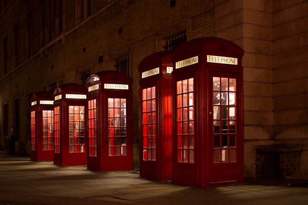 Cinque cabine telefoniche allineate di rosso vicino all'edificio