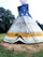 A vividly painted tipi stands in an outdoor setting, surrounded by grass and trees. The tipi features colorful designs, including a large bird motif, abstract shapes, and handprints. The structure is supported by wooden poles, creating a traditional and cultural aesthetic.