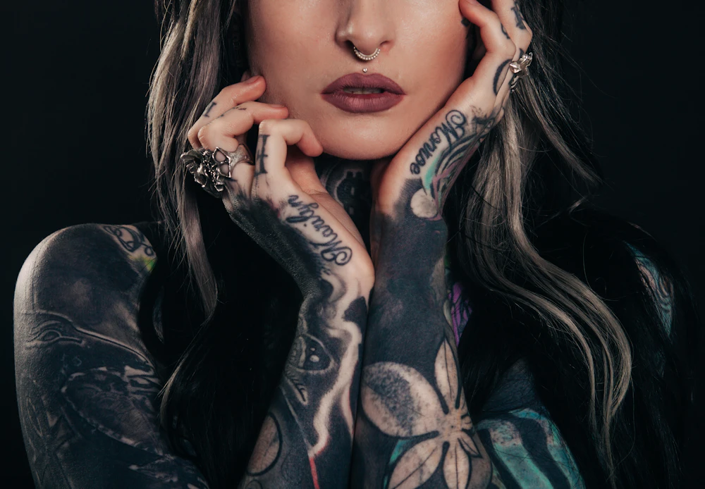 Woman with tattooed hands and fingers resting against her face