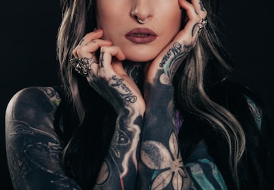 woman showing body tattoo while holding her face tattoo zoom background