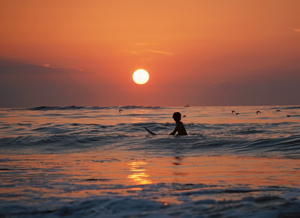 silhouette photo of person riding a surfboard