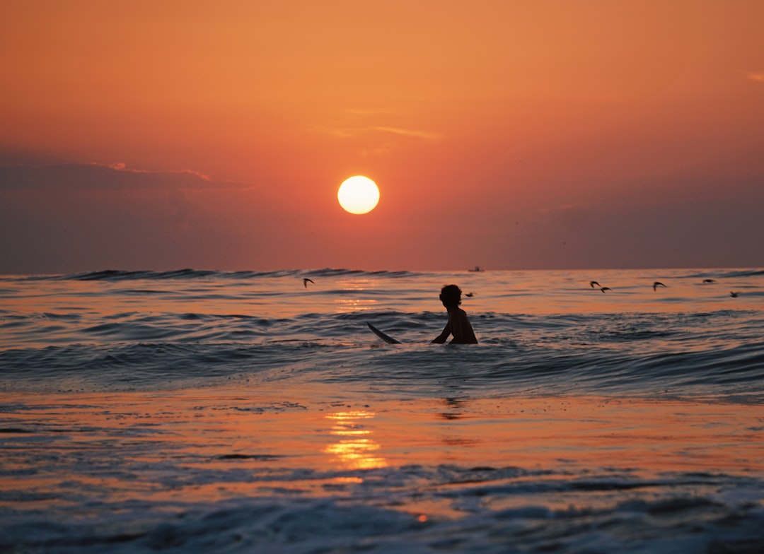 silhouette photo of person riding a surfboard, Ocean City sunset surfing