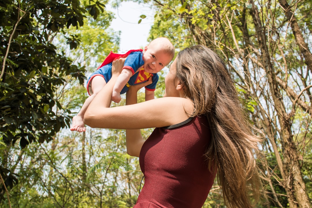 Mãe segurando o filho bebê com roupa de super herói na natureza