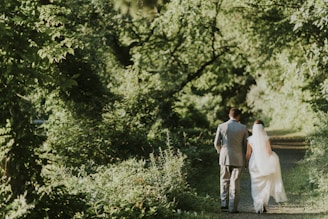 groom and bride walking on forest pathway photograph