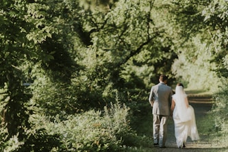 groom and bride walking on forest pathway photograph