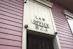 A close-up view of an exterior building wall with horizontal paneling painted in a soft pink color. The central focus is a large rectangular plaque stating 'LAW OFFICE 823' in bold letters. The paneling and design suggest a historical or vintage style.