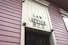 A close-up view of an exterior building wall with horizontal paneling painted in a soft pink color. The central focus is a large rectangular plaque stating 'LAW OFFICE 823' in bold letters. The paneling and design suggest a historical or vintage style.
