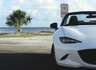 A rental car parked beside a beach, ready for a road trip.