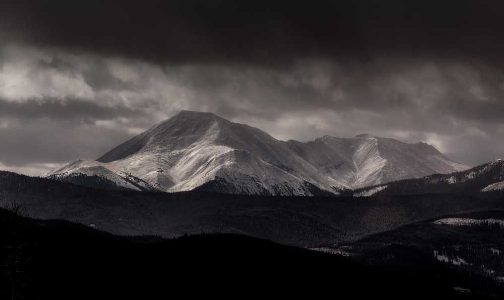 grayscale photography of mountain under cloudy sky