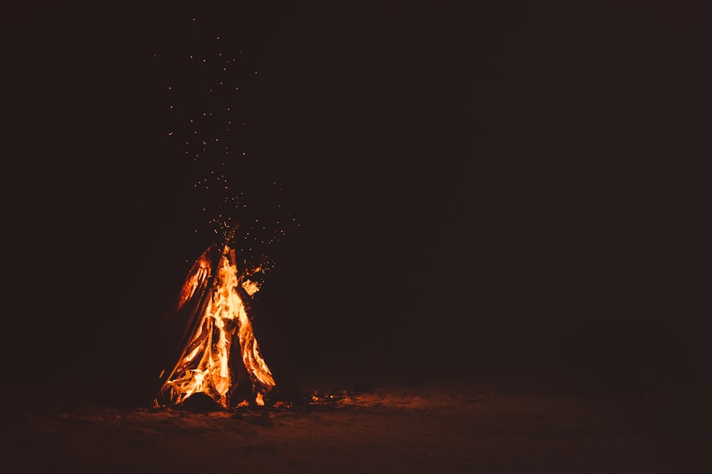 Lagerfeuer auf braunem Sand während der Nacht