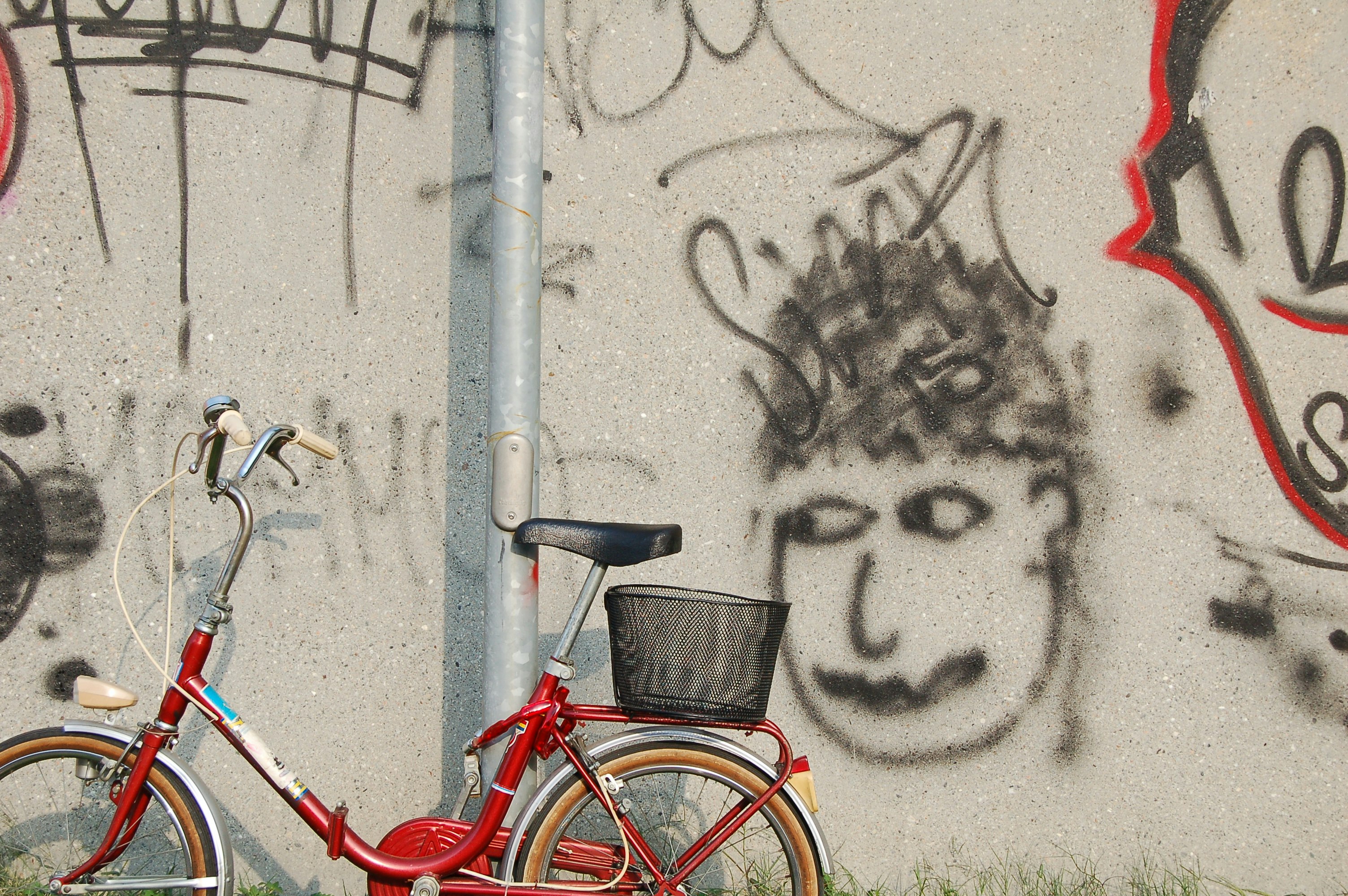 red female beach cruiser bike parks beside gray post