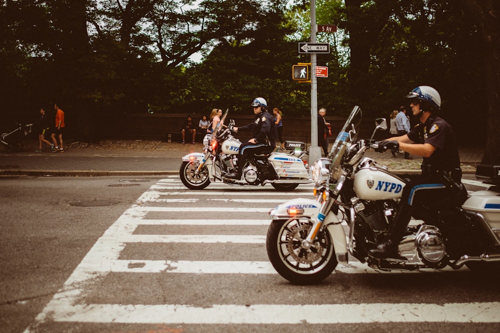 two policemen riding motorcycles on road
