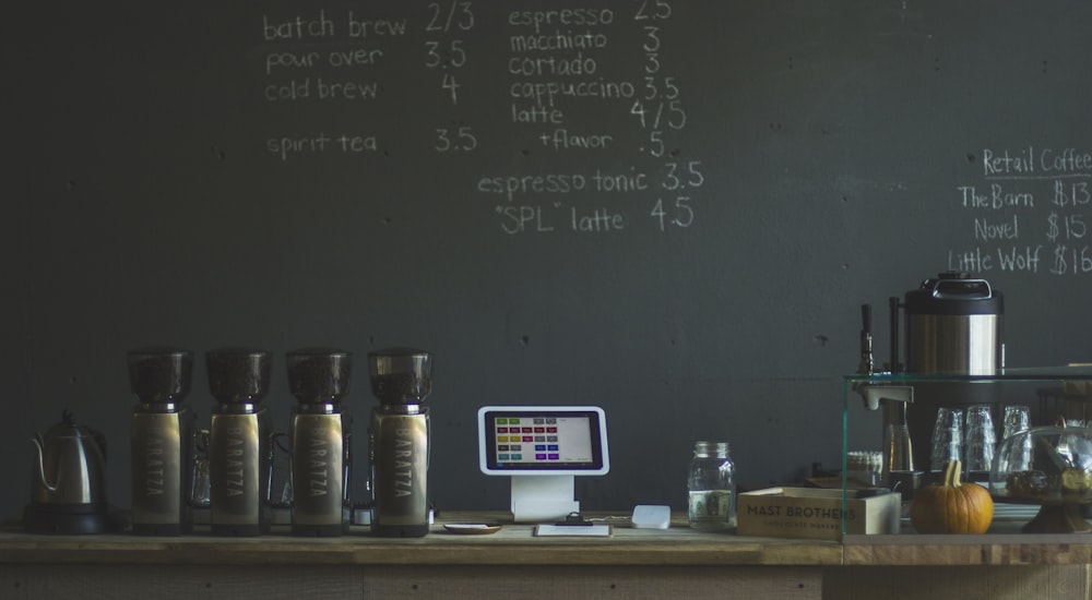 grey stainless steel bottles beside greenboard