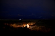 A cozy beachside campfire setting with soft lantern light and starry night sky.
