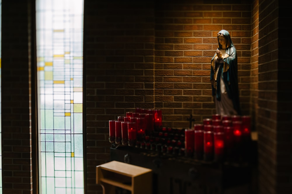 estatueta religiosa no canto com lote de porta-velas vermelho