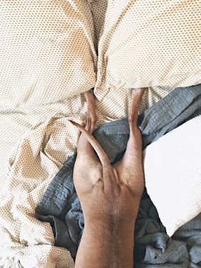 Perro descansando sobre una cama con sábanas amarillas de lunares, acostado boca abajo con las patas