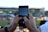 Close-up of a smartphone displaying live sports scores with a blurred stadium background.