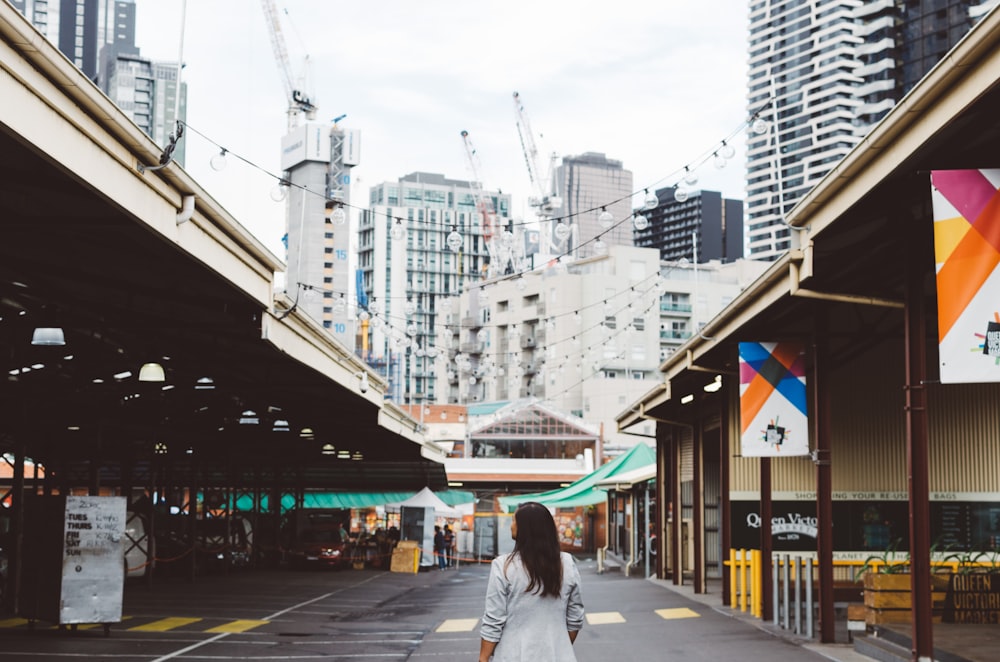 photo of woman standing on roadway between buildings