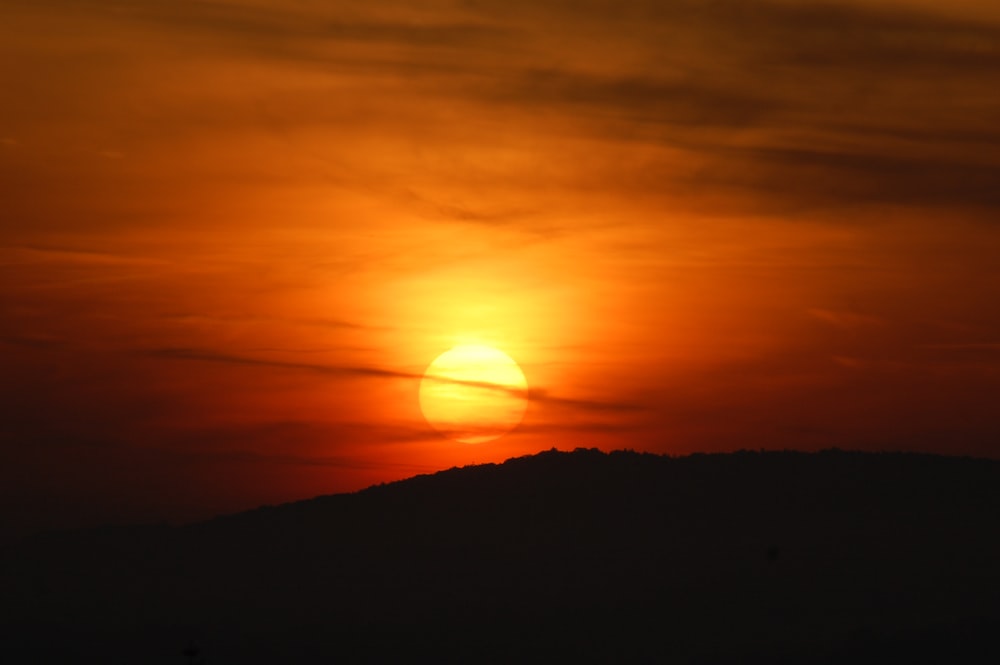 オレンジ色の夕暮れ時の山のシルエット