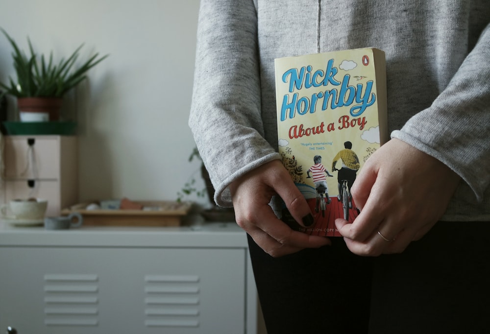 person holding Nick Hornby's About a Boy book