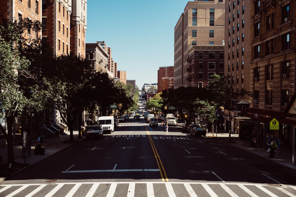 vehicles on concrete road between buildings at daytime