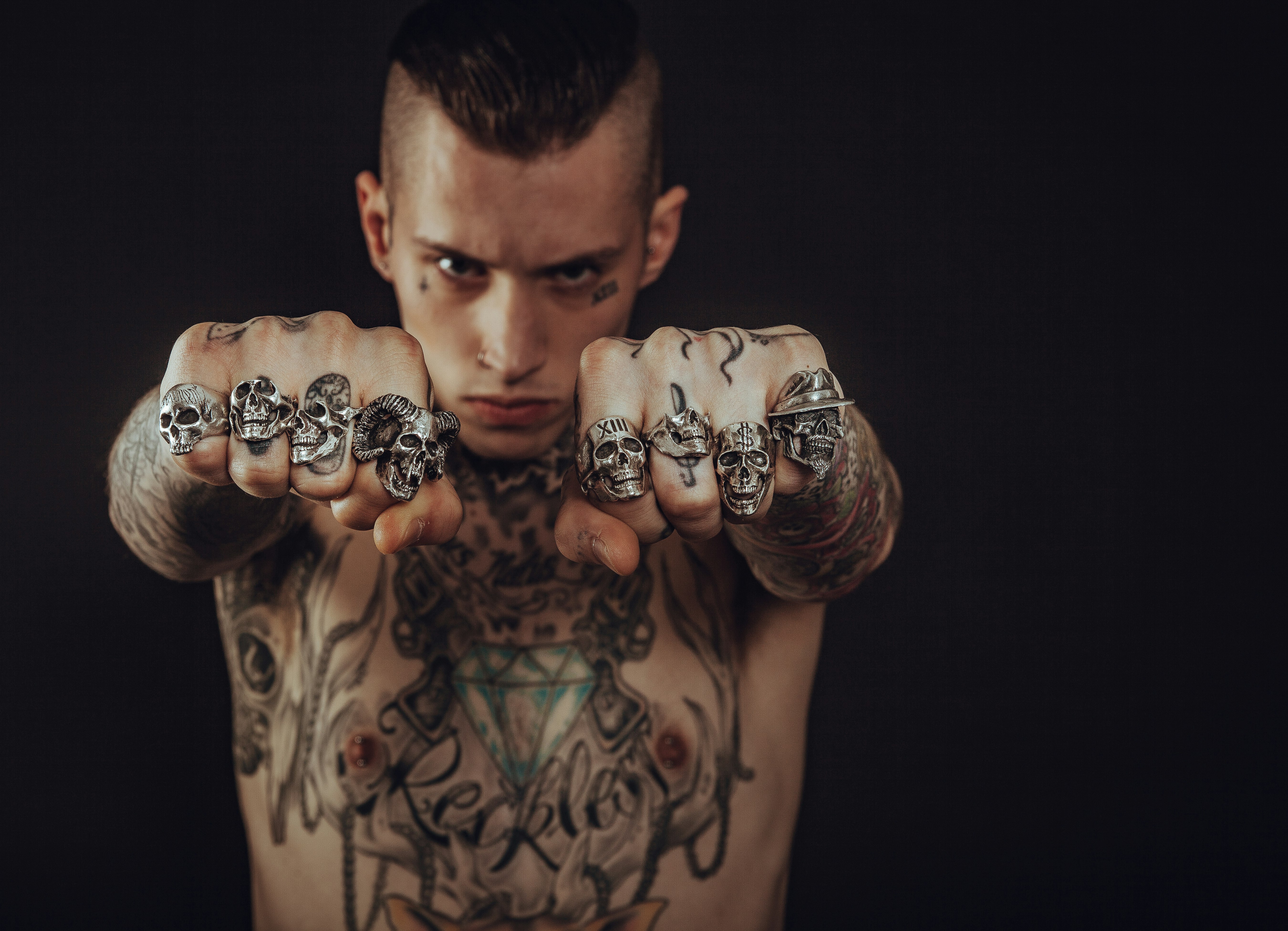 topless man showing his hands with nine silver-colored rings