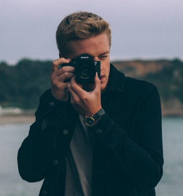 shallow photography of man holding camera