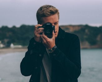 shallow photography of man holding camera