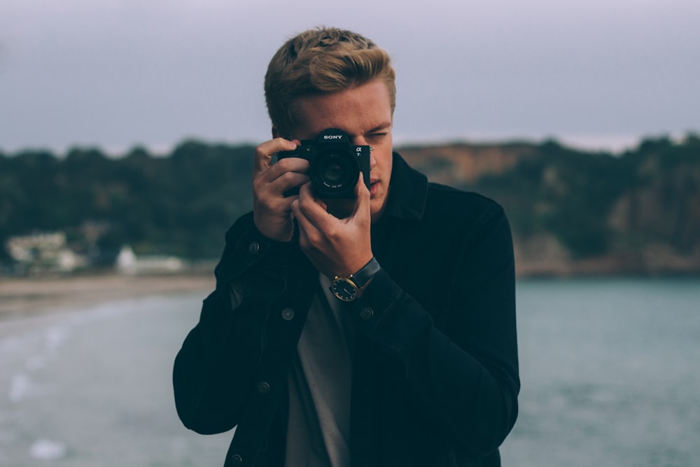 shallow photography of man holding camera