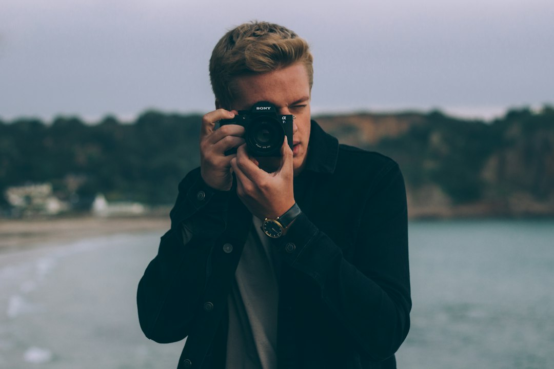 shallow photography of man holding camera,