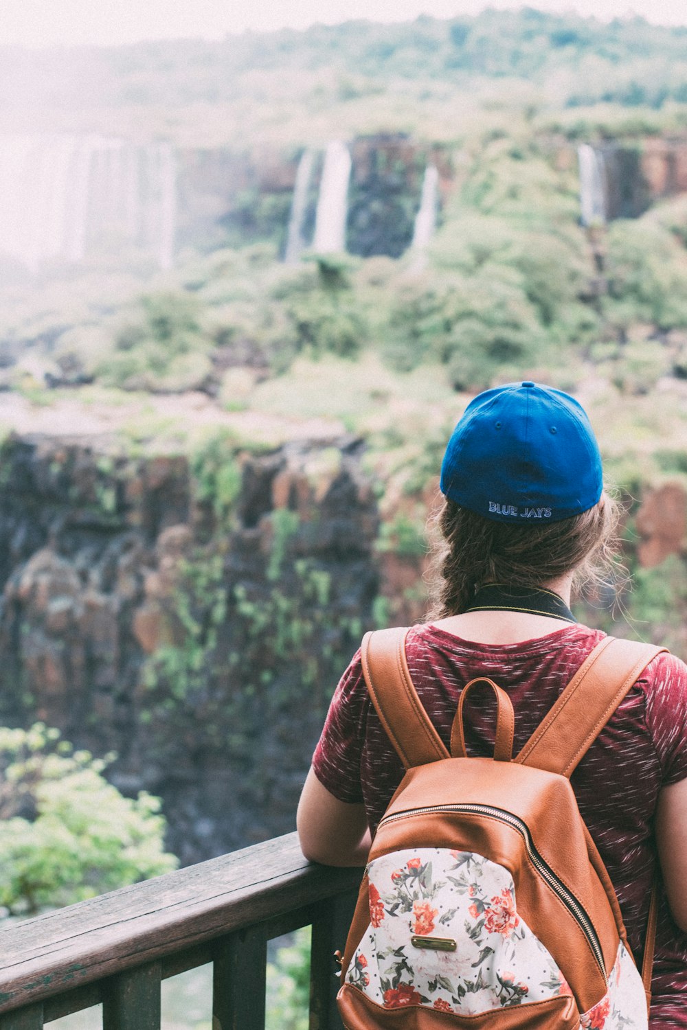 woman in brown leather backpack looking at green trees during daytime