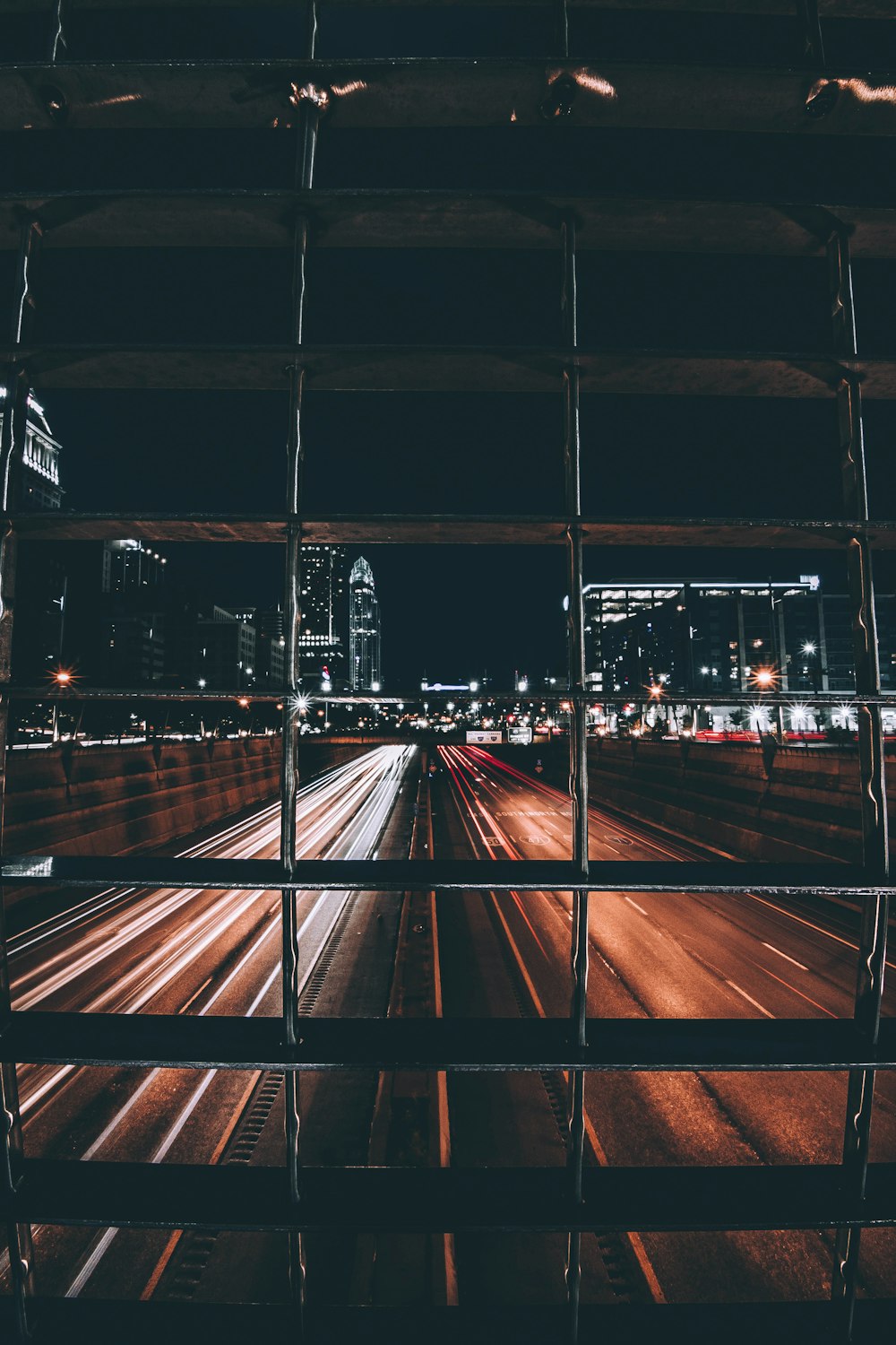 time-lapse photo of road with light streaks view behind grills