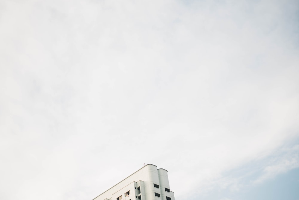 a tall white building sitting under a cloudy blue sky