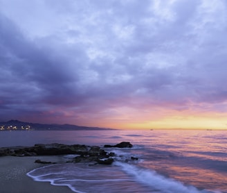 waves of body of water splashing on sand