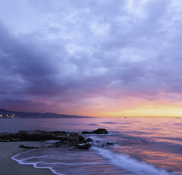 waves of body of water splashing on sand