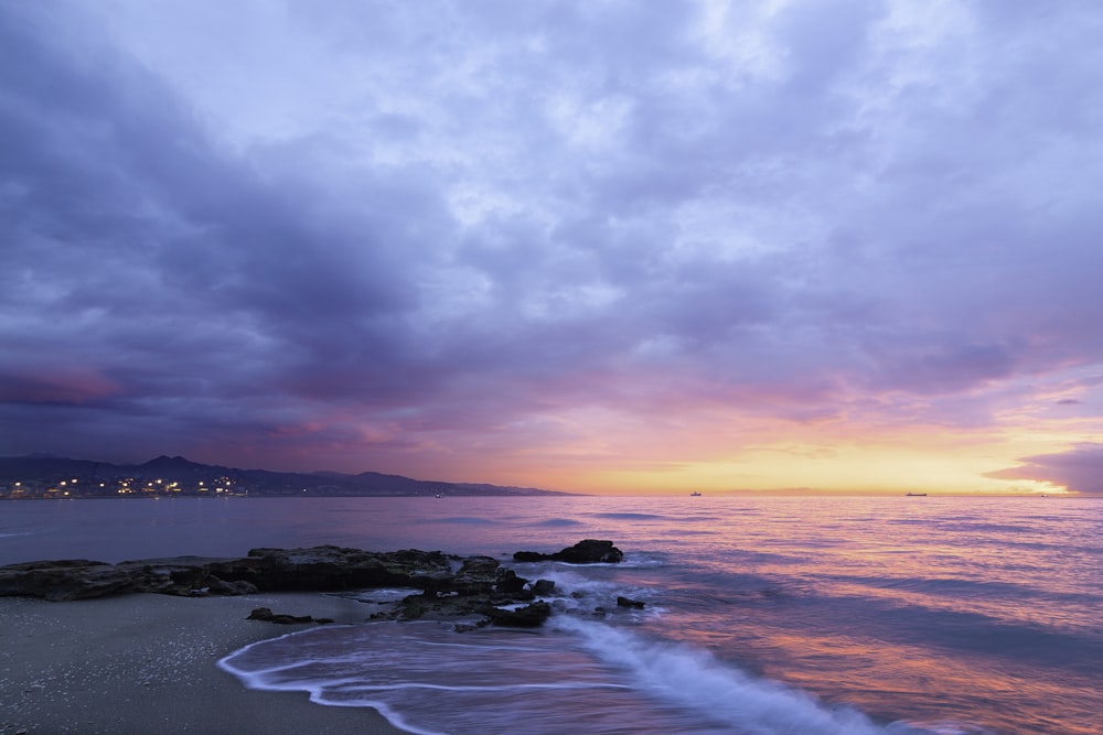 waves of body of water splashing on sand