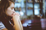 A young woman praying quietly before starting her entrepreneurial work on a laptop.