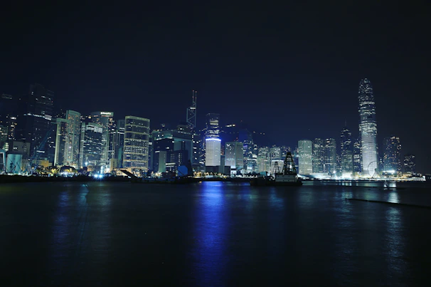 A vibrant city skyline glowing at night with twinkling lights and reflections.