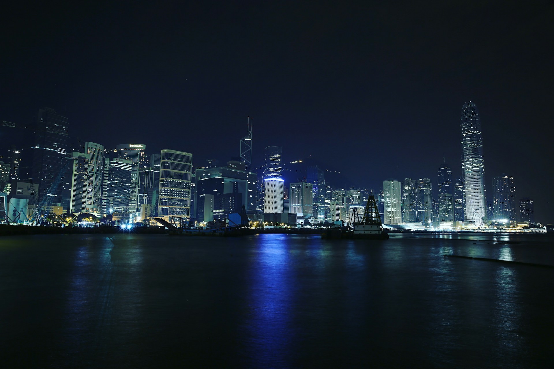 A vibrant cityscape at sunset with glowing lights reflecting off the water.